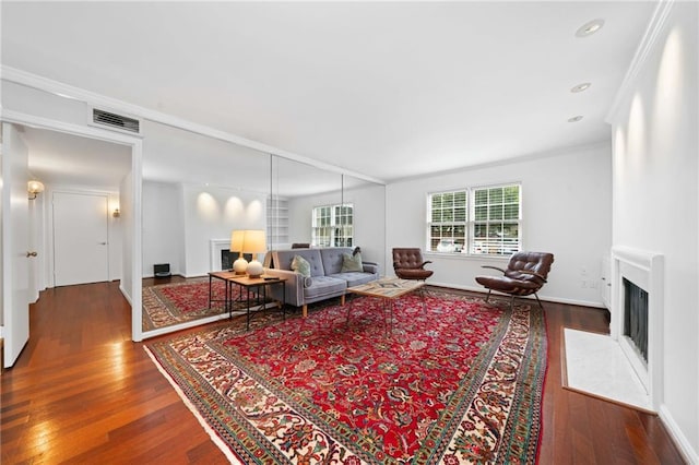 living room with a fireplace with flush hearth, hardwood / wood-style flooring, ornamental molding, baseboards, and recessed lighting
