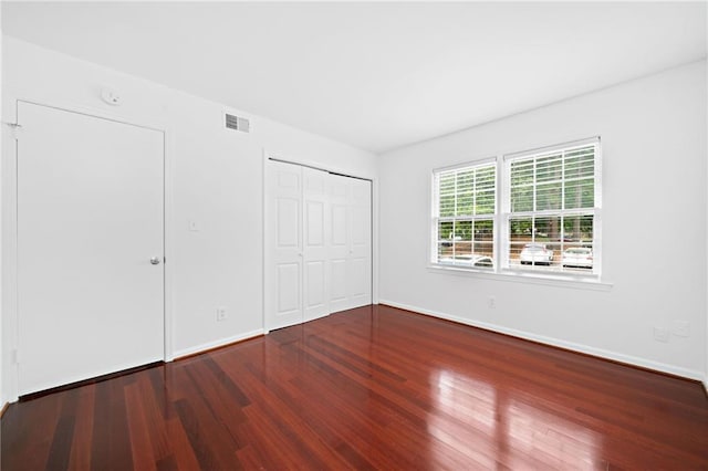 unfurnished bedroom with wood finished floors, baseboards, and a closet
