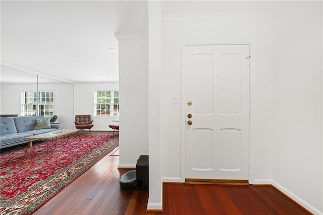 foyer with wood finished floors, baseboards, and ornamental molding