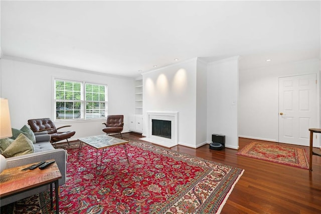 living area with wood finished floors, ornamental molding, a fireplace with flush hearth, and recessed lighting