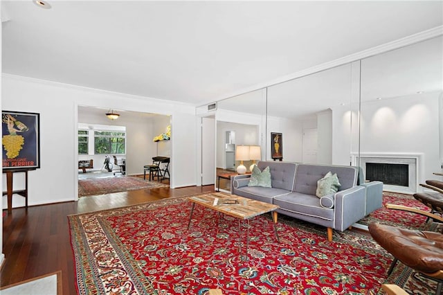 living room featuring hardwood / wood-style floors, crown molding, and a fireplace