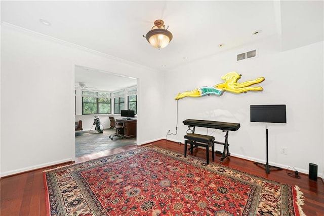 interior space featuring wood finished floors, baseboards, and crown molding