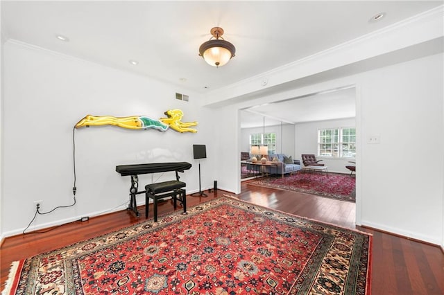 living area featuring wood finished floors, ornamental molding, and baseboards