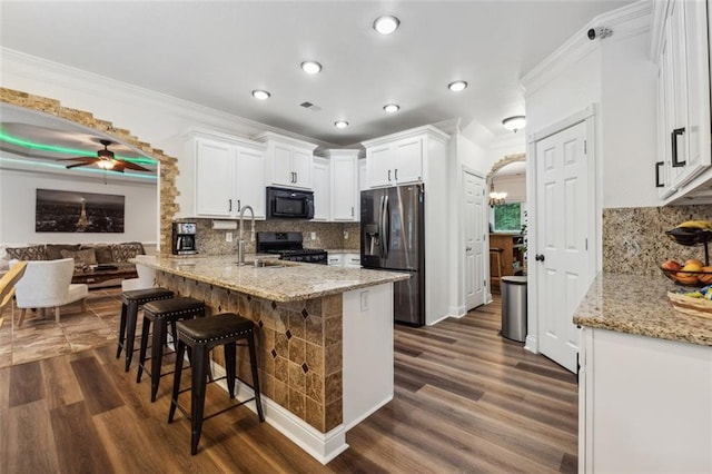 kitchen with kitchen peninsula, white cabinets, tasteful backsplash, and black appliances