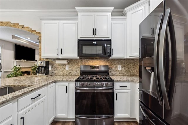 kitchen with decorative backsplash, white cabinets, stainless steel appliances, and light stone counters