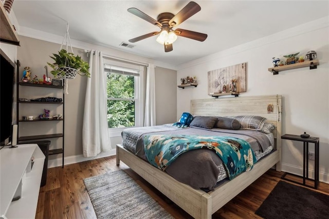 bedroom featuring dark hardwood / wood-style flooring, ceiling fan, and crown molding