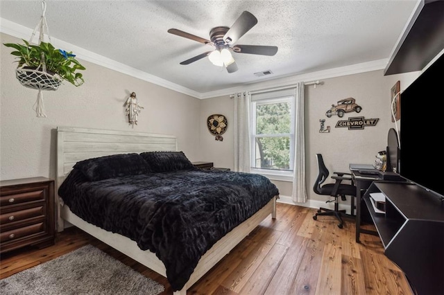 bedroom featuring ceiling fan, hardwood / wood-style floors, a textured ceiling, and ornamental molding