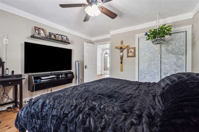 bedroom with ceiling fan, crown molding, a textured ceiling, and hardwood / wood-style flooring