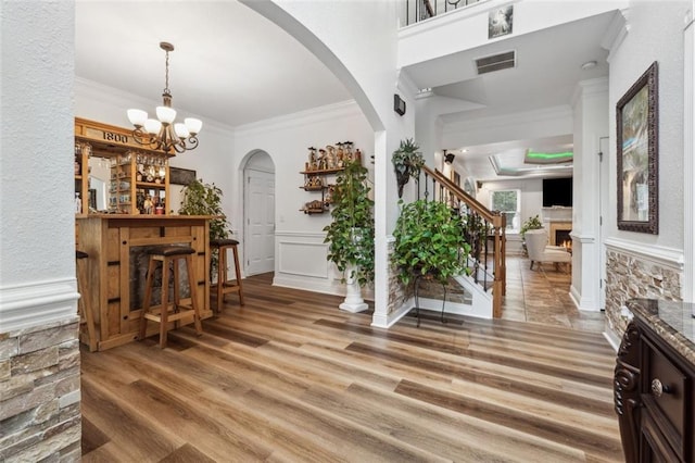 entryway featuring bar area, hardwood / wood-style flooring, an inviting chandelier, and crown molding