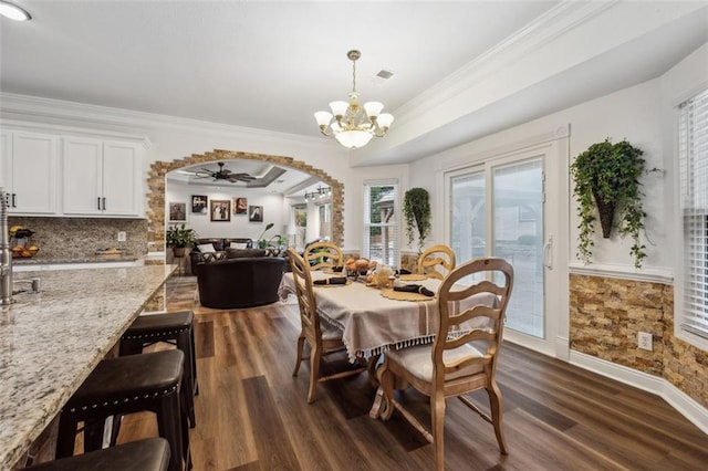 dining room featuring dark hardwood / wood-style floors, ceiling fan with notable chandelier, and ornamental molding