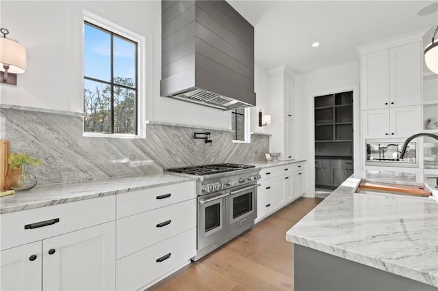 56 Pine St, Roswell, GA 30075 - kitchen featuring double oven range, wall chimney range hood, a sink, backsplash, and white cabinets