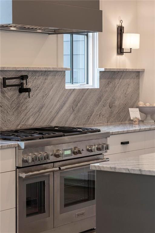 56 Pine St, Roswell, GA 30075 - kitchen with double oven range, wall chimney exhaust hood, white cabinets, tasteful backsplash, and light stone counters