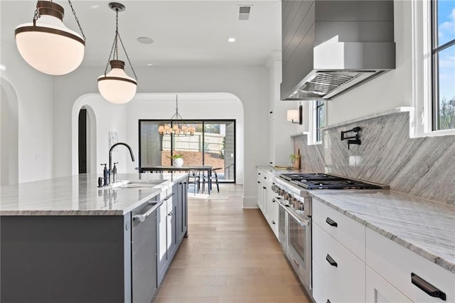 56 Pine St, Roswell, GA 30075 - kitchen with stainless steel appliances, a sink, wall chimney range hood, arched walkways, and a chandelier