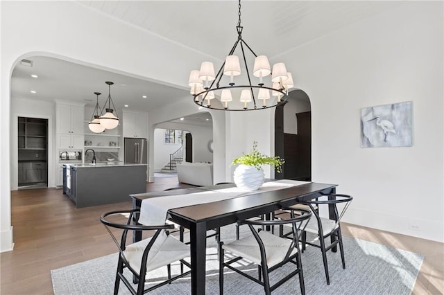 56 Pine St, Roswell, GA 30075 - dining area featuring arched walkways, a chandelier, light wood-style floors, recessed lighting, and stairway