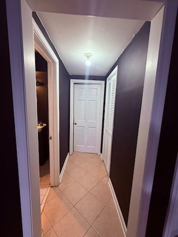corridor with baseboards and light tile patterned floors