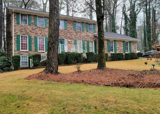 colonial house featuring brick siding and a front yard