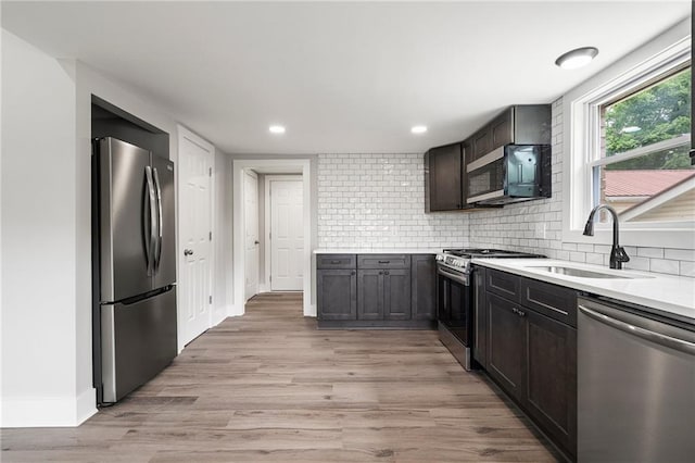 kitchen with stainless steel appliances, light wood-style floors, light countertops, and a sink