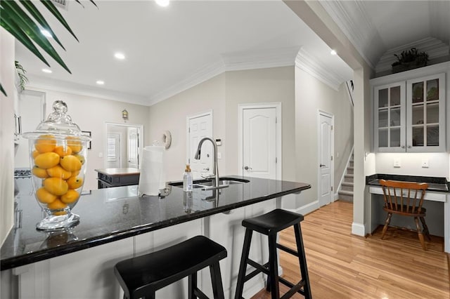 8730 Parker Pl, Roswell, GA 30076 - kitchen with a sink, light wood-style floors, crown molding, a kitchen bar, and glass insert cabinets