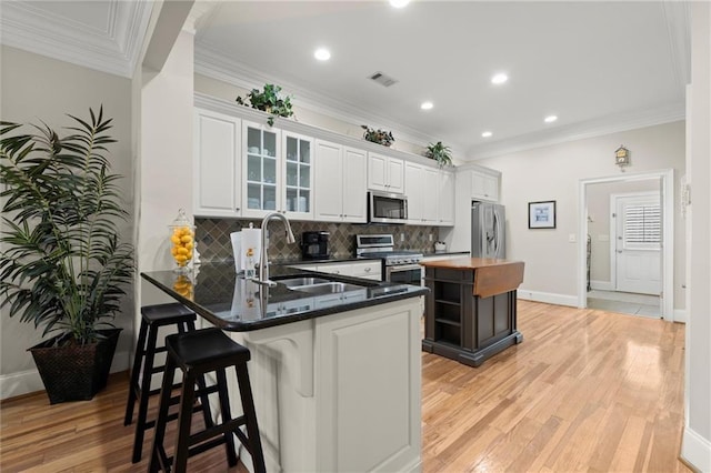 8730 Parker Pl, Roswell, GA 30076 - kitchen with appliances with stainless steel finishes, a sink, decorative backsplash, white cabinets, and a breakfast bar