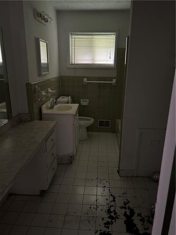 bathroom with toilet, a tub to relax in, tile walls, tile patterned floors, and vanity