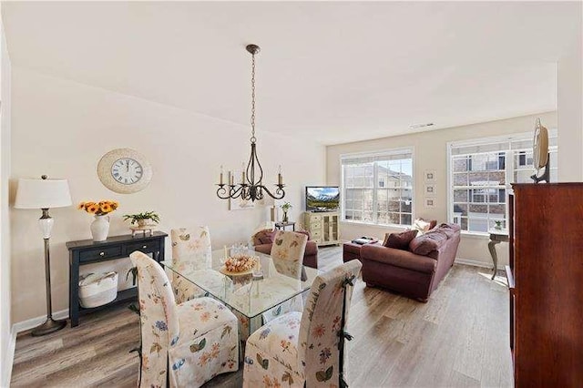 dining area featuring wood-type flooring and an inviting chandelier