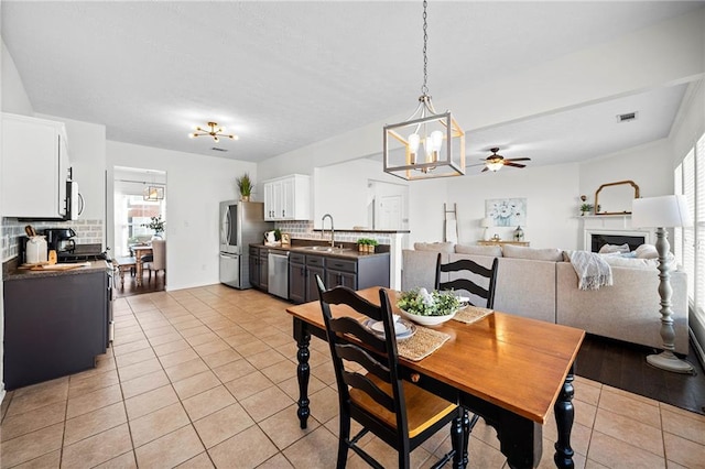 kitchen with stainless steel appliances, light tile patterned floors, dark countertops, white cabinets, and decorative backsplash