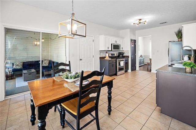 dining room with ceiling fan with notable chandelier, visible vents, and light tile patterned floors