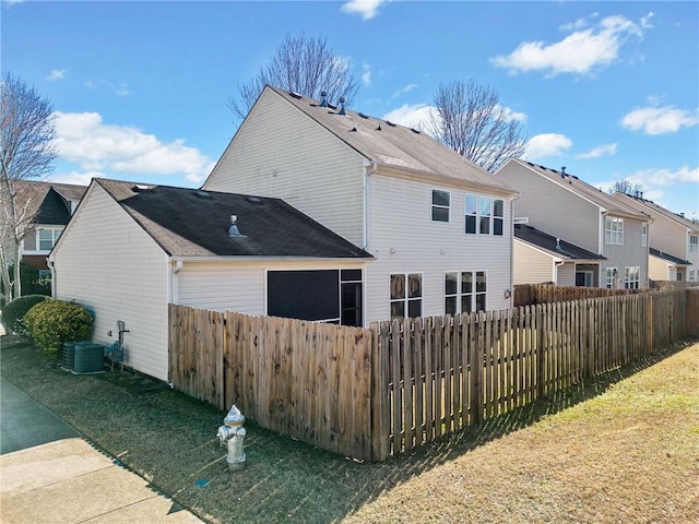 rear view of house featuring a sunroom, a fire pit, fence, and a lawn