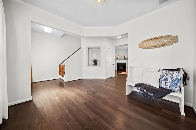 foyer with baseboards, a fireplace, wood finished floors, and ornamental molding