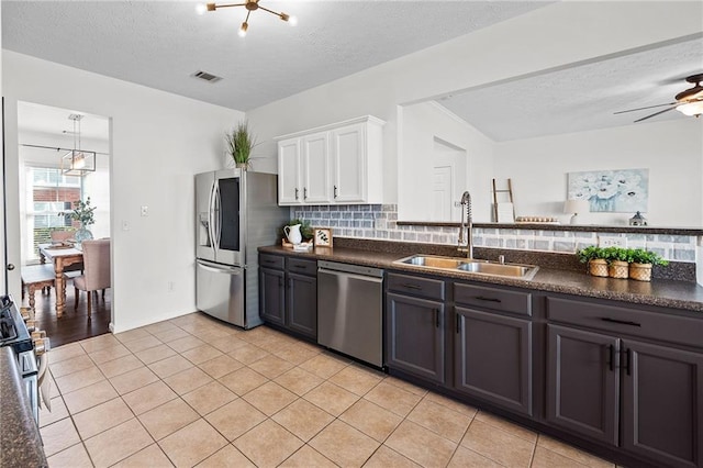 kitchen featuring a sink, tasteful backsplash, appliances with stainless steel finishes, dark countertops, and visible vents