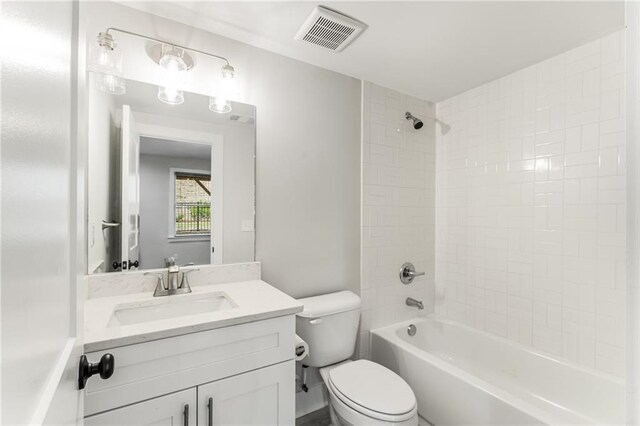 full bathroom with tiled shower / bath, vanity, and toilet