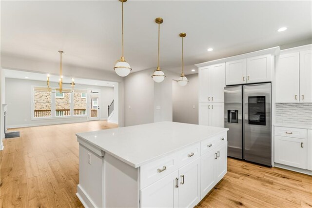 kitchen with stainless steel fridge, hanging light fixtures, white cabinetry, light hardwood / wood-style floors, and a center island