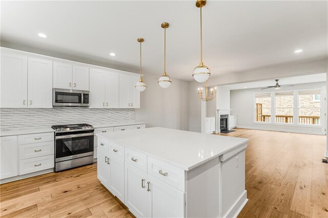 kitchen featuring white cabinets, appliances with stainless steel finishes, a center island, and hanging light fixtures