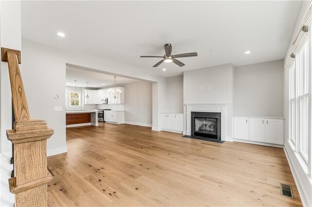 unfurnished living room featuring light wood-type flooring, plenty of natural light, and ceiling fan