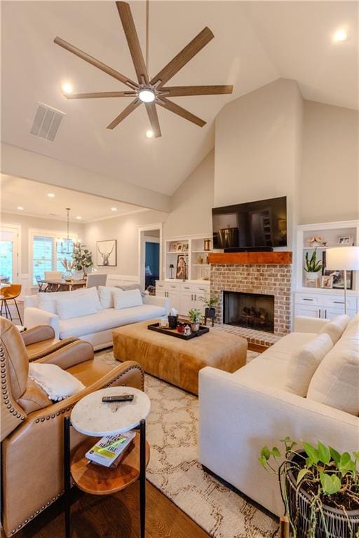 living room with high vaulted ceiling, wood-type flooring, ceiling fan, a brick fireplace, and built in shelves