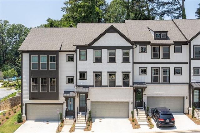 townhome / multi-family property with concrete driveway, an attached garage, and a shingled roof