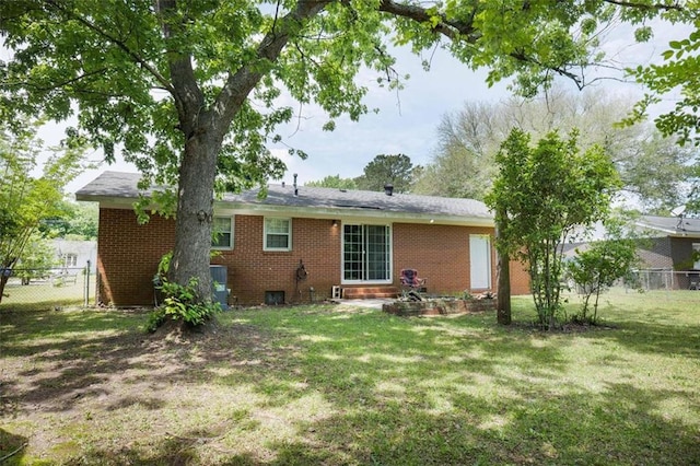 rear view of property featuring fence, a yard, and brick siding