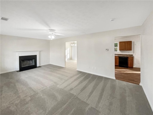 unfurnished living room featuring visible vents, a fireplace with flush hearth, baseboards, ceiling fan with notable chandelier, and carpet