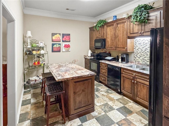 kitchen featuring a center island, a kitchen bar, ornamental molding, decorative backsplash, and black appliances