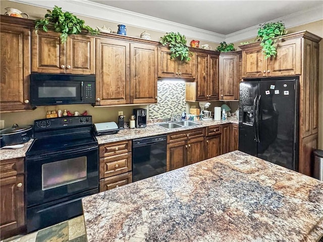 kitchen with light stone countertops, ornamental molding, decorative backsplash, black appliances, and a sink