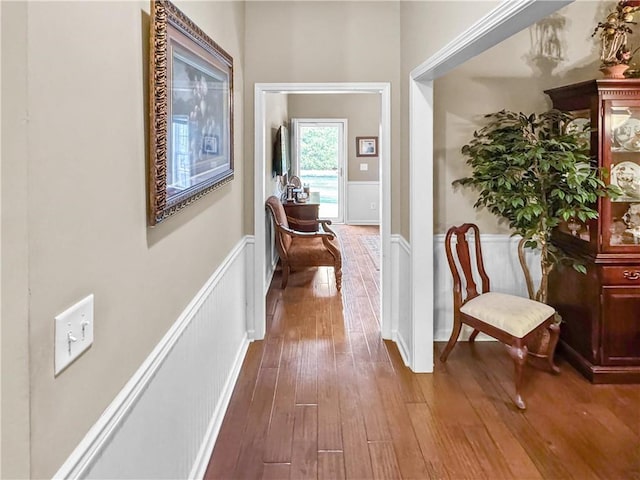 hall with a wainscoted wall, a decorative wall, and hardwood / wood-style floors