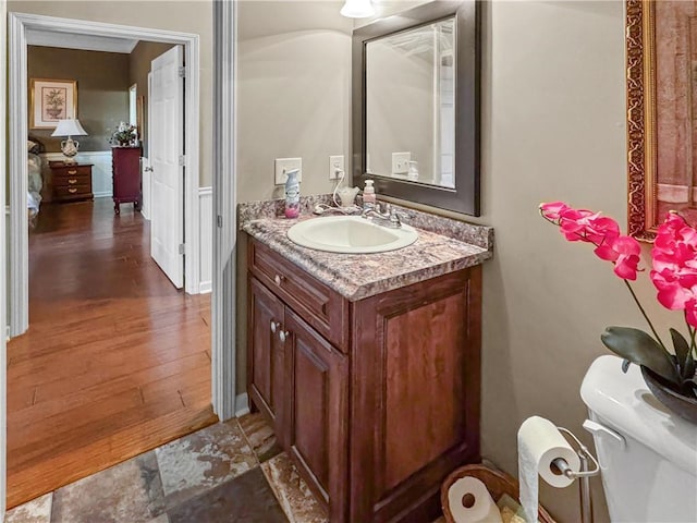 bathroom featuring vanity, toilet, wood finished floors, and baseboards