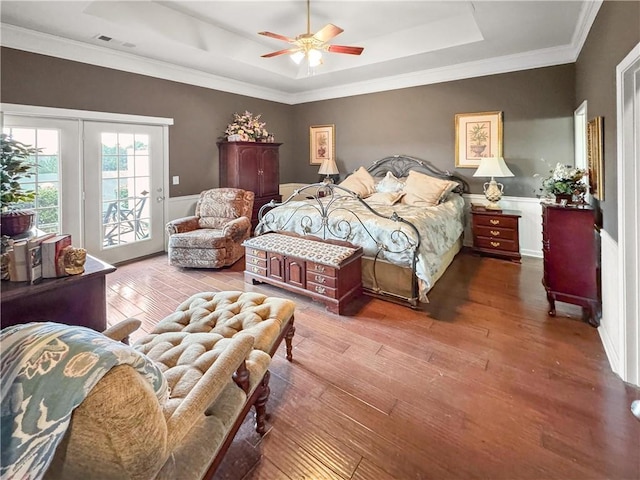 bedroom with a ceiling fan, wood finished floors, visible vents, a raised ceiling, and access to outside