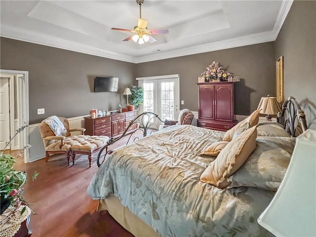 bedroom featuring a tray ceiling, wood finished floors, french doors, and ceiling fan