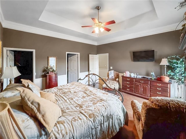 bedroom with light wood finished floors, a wainscoted wall, ceiling fan, and a tray ceiling