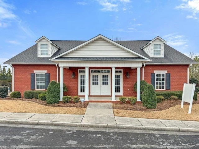 view of front of home featuring brick siding and roof with shingles