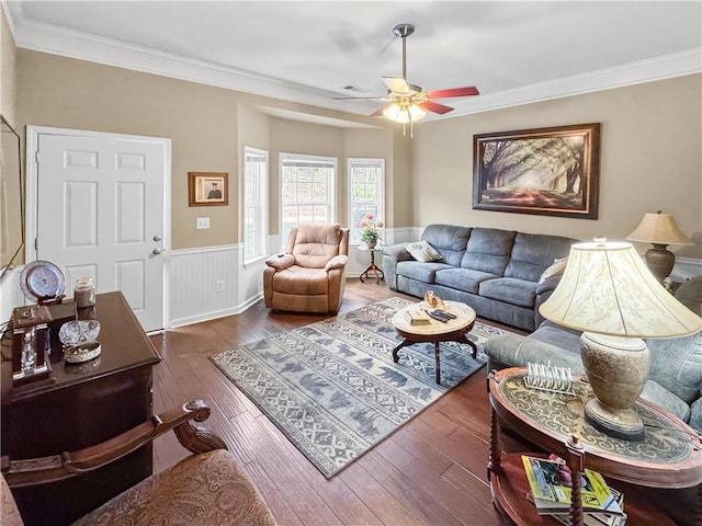 living room featuring crown molding, a wainscoted wall, wood-type flooring, and ceiling fan