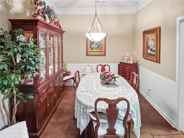 dining space featuring dark wood finished floors, crown molding, and wainscoting