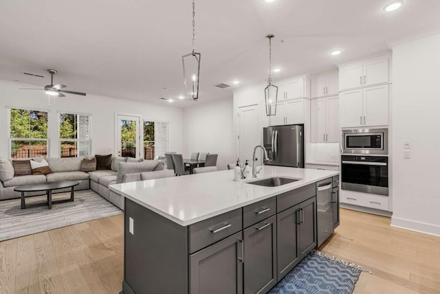 kitchen with white cabinetry, stainless steel appliances, a sink, and light countertops