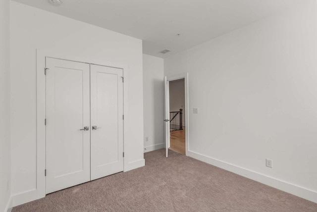 unfurnished bedroom with a closet, carpet flooring, and baseboards